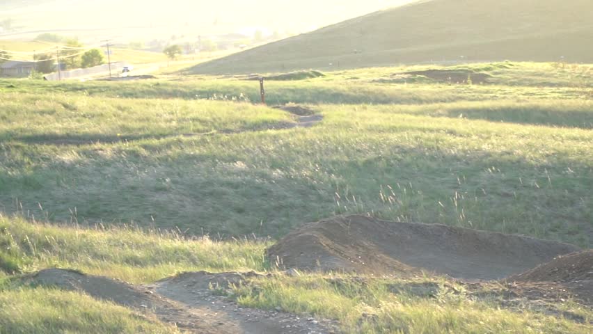 Mountain bikers on dirt track with jumps at sunset. Erie, Colorado