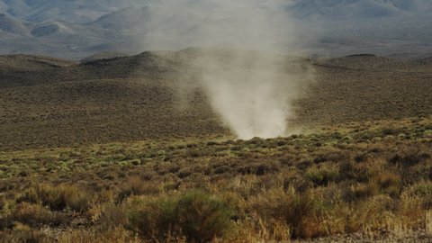 Dust devil, desert tornado churns through the dry Mojave desert scrub