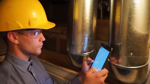 Young white man wearing a safety hard hat and safety glasses going a home inspection with a tablet 