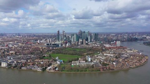 Aerial bird's eye view panoramic drone video of Canary Wharf skyline as seen from University of Greenwich with beautiful cloudy sky, Isle of Dogs, London, United Kingdom