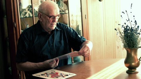 Happy, senior man playing cards by table at home, 4K 
