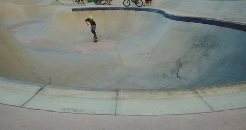 Young skateboarder grinding the coping in a pool bowl, extreme shredder skateboarder kid in skatepark, slow motion