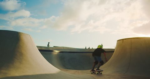 Skateboarder kid flying through the air in skate park at sunset, extreme skateboarding kid jumping high, young skateboarding shredder in slow motion