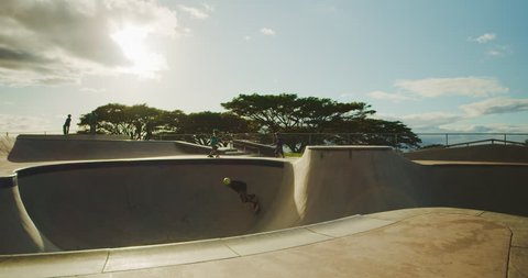 Young skateboarder grinding the coping in a pool bowl at sunset, extreme shredder skateboarder kid in skatepark, slow motion