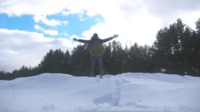 concept freedom. man winter hands to the side stands in the snow next to the forest slow motion video. hike tourist in the snow with a backpack winter snow lifestyle
