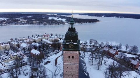 Drone footage whileing away from the old cathedral of Strängnäs revealing the old town. A frozen lake is in the background. Filmed in realtime at 4k.