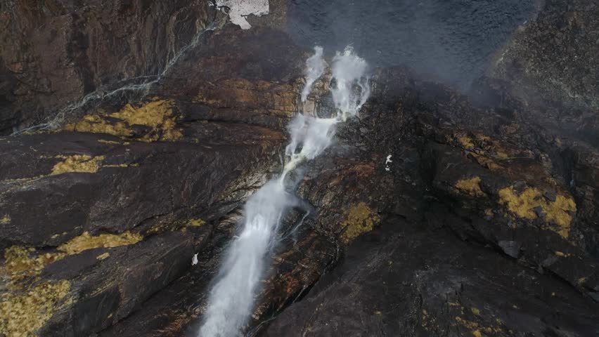 Aerial pan over two large waterfalls in the mountains of Norway with snow
