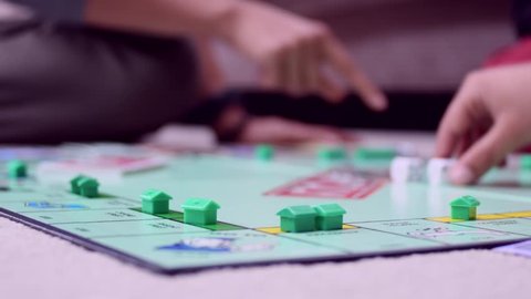 Leicester, United Kingdom (UK) - 10 05 2018: Ground level view of children and adults playing the classic board game Monopoly.