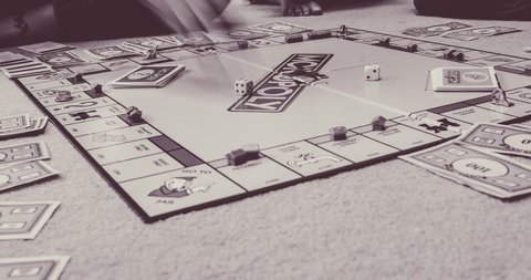 Leicester, United Kingdom (UK) - 10 05 2018: Ground level time lapse view of children and adults playing the classic board game Monopoly - in black and white.