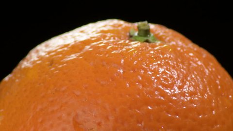 Natural orange fruit gyrating on black background