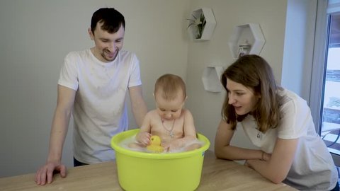 mom and dad bathe daughter at home
