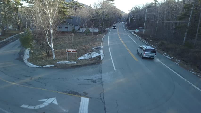 Aerial view by drone of a car driving on a road to a laboratory in the middle of a forest in Acadia National Park, Maine, USA