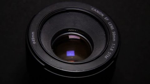 Vilnius, Lithuania - 10 05 2018: Close Up of DSLR Camera Lens Canon 50mm f1.8 in the Dark. Moving LED Light Panel Reflections in Objective Glasses.