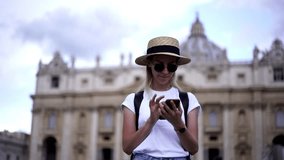 Stylish female tourist in sunglasses enjoying trip to Vatican city making panoramic video via smartphone camera, positive hipster girl with backpack clicking selfie photo in summer vacations holidays