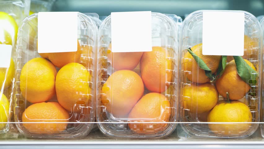 Footage of plastic containers with ripe orange fruits in food aisle at supermarket.Buy natural fruit for healthy nutrition.Video of oranges and mandarins packed in transparent boxes in foods market  | Shutterstock HD Video #1026480281