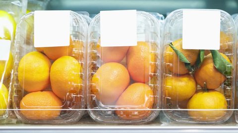 Footage of plastic containers with ripe orange fruits in food aisle at supermarket.Buy natural fruit for healthy nutrition.Video of oranges and mandarins packed in transparent boxes in foods market 