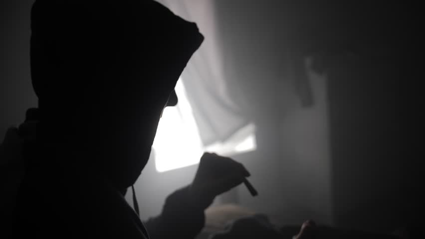 A young man lights up a marijuana joint and smokes it.