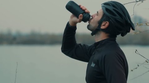 Cyclist Drinking Water On Water Bottle. Triathlete Use Isotonic Drink On Triathlon Sport. Athlete Cyclist Man Hydration After MTB Cycling Bike Training. Sportsman Drinking On Cycling. Sport Recreation