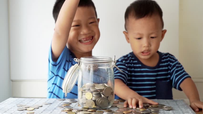 Slow motion children drops coin money into glass jar, financial concept. | Shutterstock HD Video #1026483995