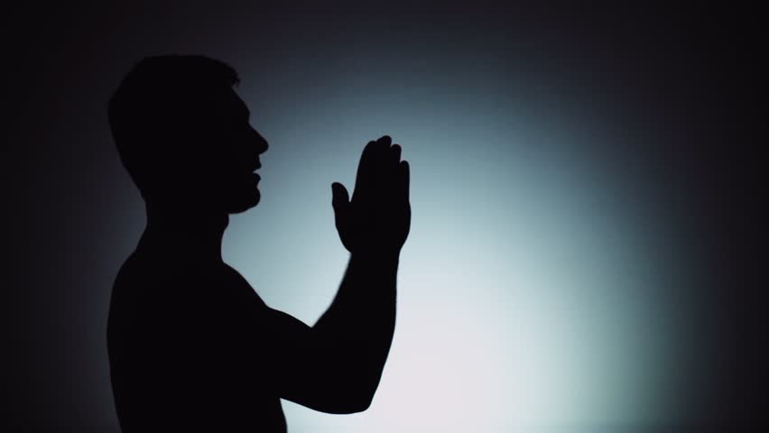 Silhouette of a man. The shadow of a man on a light background. A man prays to God, folding his arms and stretching them up. Emotions, prayer, religion, faith. | Shutterstock HD Video #1026492023