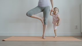 YOGA: Slender mom with her pretty little daughter practising yoga on a mat at home - Front View - Powered by Shutterstock - Get 15% off with code: PIKWIZARD15