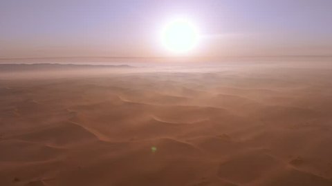 4K drone shoot through the sun of Liwa desert early morning in Abu Dhabi, UAE. Sand storm and foggy weather.