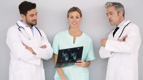 Doctors and nurse talking over X-Ray on grey background