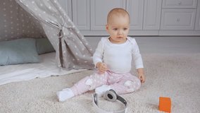 cute smiling child sitting on rug near headphones while playing with ball