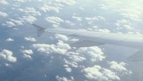 Stunning footage of aerial view above clouds from airplane window with blue sky. view of the earth from the sky through the clouds. 4K video. Aerial footage. Travel concept