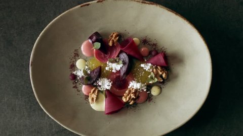 Plated presentation of dish of beets, cheese and walnuts on a fancy dish on a counter. Close up shot on 4k RED camera.