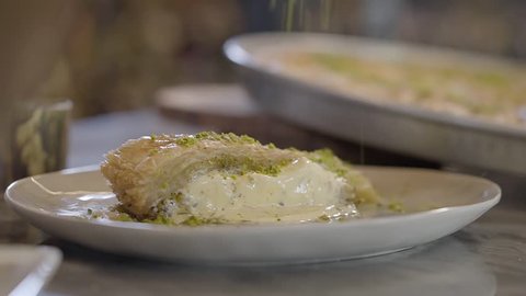 Eastern sweet dish kunafa with cheese sprinkling with pistachios on the table close up. Food preparation in restaurant. Turkish cuisine