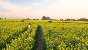 Descending crane 4K video clip of beautiful happy mixed race African American girl teenager female young woman hiking with red backpack and bottle of water in field of yellow flowers