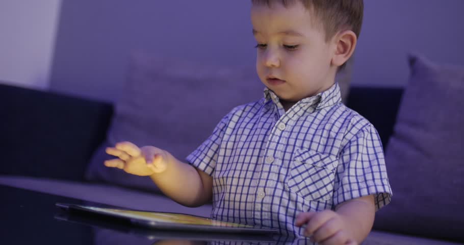 Cute Child Entertaining With Tablet. Little Boy Spending Leisure Time Playing Mobile Game in the and Crushes the Bright Screen With Her Hand. Concept of:Happy Childfood, Technology, Childen Play Games | Shutterstock HD Video #1026524723