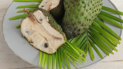 Closeup of green soursop graviola, exotic, fruit Guanabana on plate, Rotate