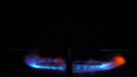 Kitchen burner flaming in the night, closeup. Nobody