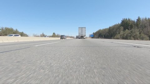 Toronto, Ontario, Canada March 2019 Driving plate of POV low angle tractor trailer trucks and cars driving on highway