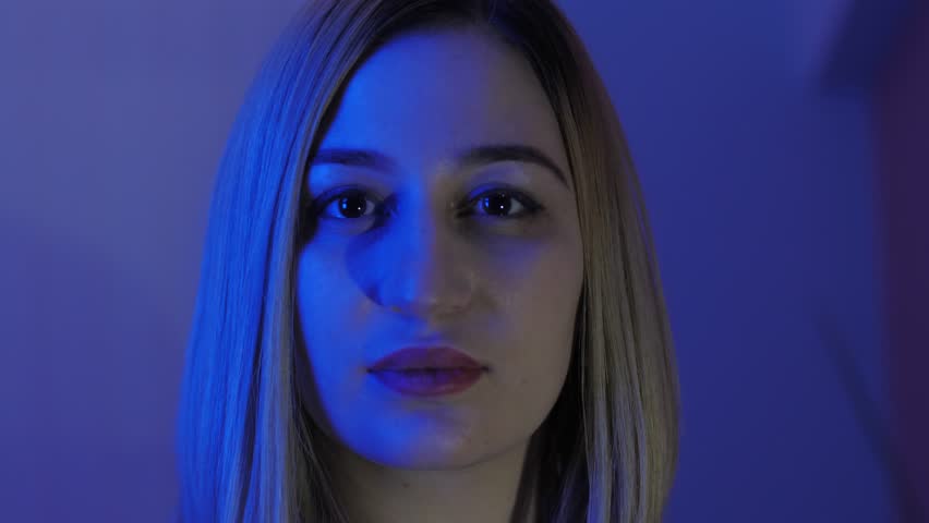 beautiful lady with loose flowing blonde hair in room with blue illumination slow motion close view