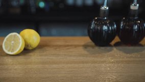 An alcoholic cocktail is put on the bar. A hand is putting a glass with a yellow cocktail and ice on the table. Food video. Video for restaurants and cafes.