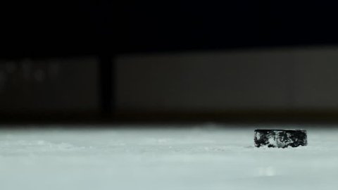 Close-up slow motion hockey puck and flying snow, hockey player picks up the puck stick