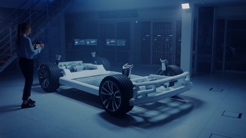 Automobile Engineer Working on Electric Car Chassis Platform, Using Tablet Computer Augmented Reality with 3D CAD Software Modelling. Innovative Facility: Vehicle Frame with Wheels, Engine, Battery