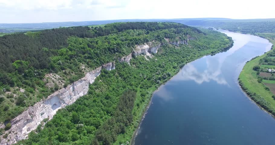 Wonderful landscape of rocks with a forest at the top and at the foot not far from river in the summer. Aerial view. Camera motion to forward.