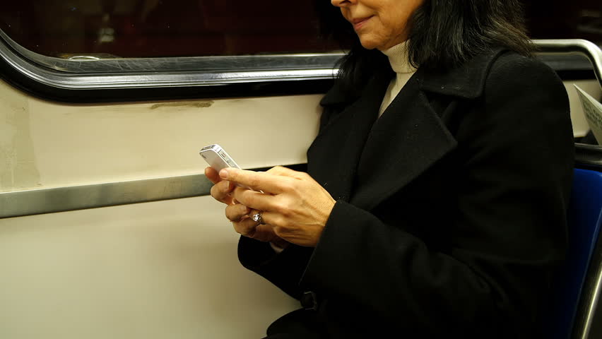 Side view of Caucasian middle aged woman using mobile phone while travelling in a train 