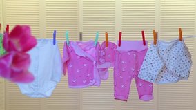 Baby white and pink cute small clothes hanging on rope isolated on white wooden background. Real time full hd video footage.