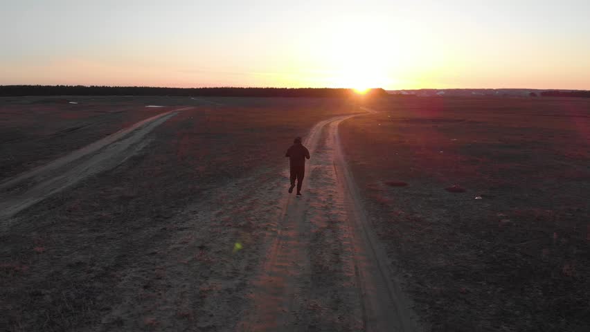 Running man silhouette in sunset time. Outdoor cross-country running. Athletic young man is running in the nature during golden sunset. Healthy lifestyle.