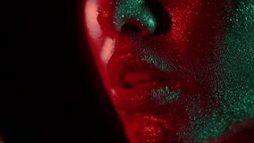 Fashion portrait of woman touching her lips with fingertips in glitter and in neon lights in 80's style, video portrait with green and red mixed neon on dark background, Shot on blackmagic 422 prores