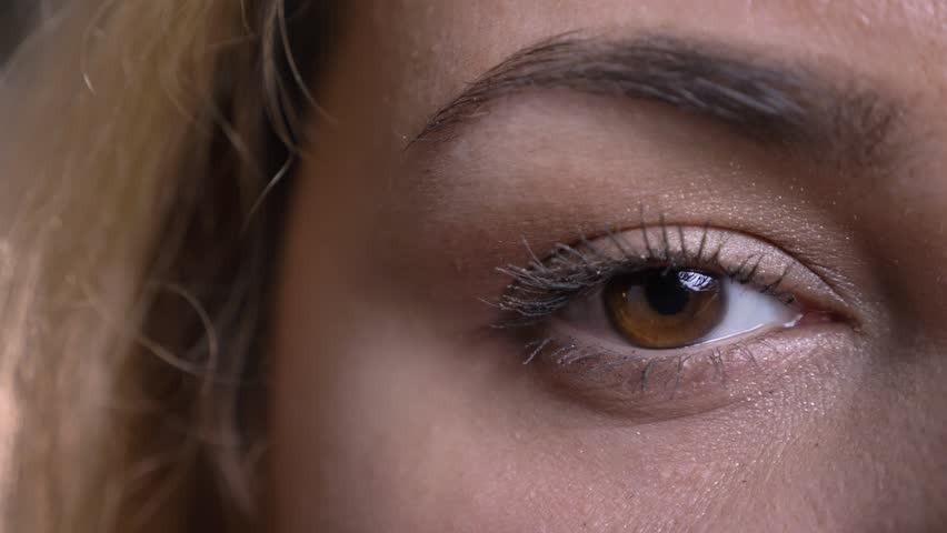 Close-up one eye-portrait of middle-aged overweight woman watches seriously and modestly on black background. | Shutterstock HD Video #1026580223