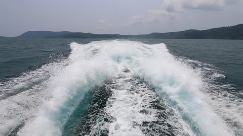 Ship wake on the ocean. Waves from the back of a public ferry boat over the water's surface foam trace ship goes till the horizon as it travels across waving bright water. View of bow waves.