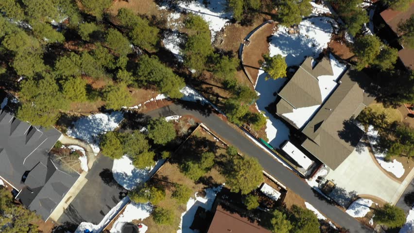 Aerial overhead drone footage Flagstaff Arizona homes with winter woods and snow