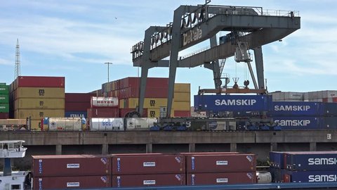 DUISBURG / GERMANY - MARCH 2019 : Gantry crane is loading a container to ship at daytime in the port of Duisburg - Germany.