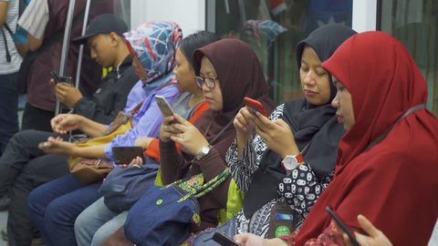 JAKARTA, Indonesia - March 26, 2019: Group of female passengers using smartphone while sitting in Mass Rapid Transit (MRT) subway train Jakarta. Shot in 4k resolution
